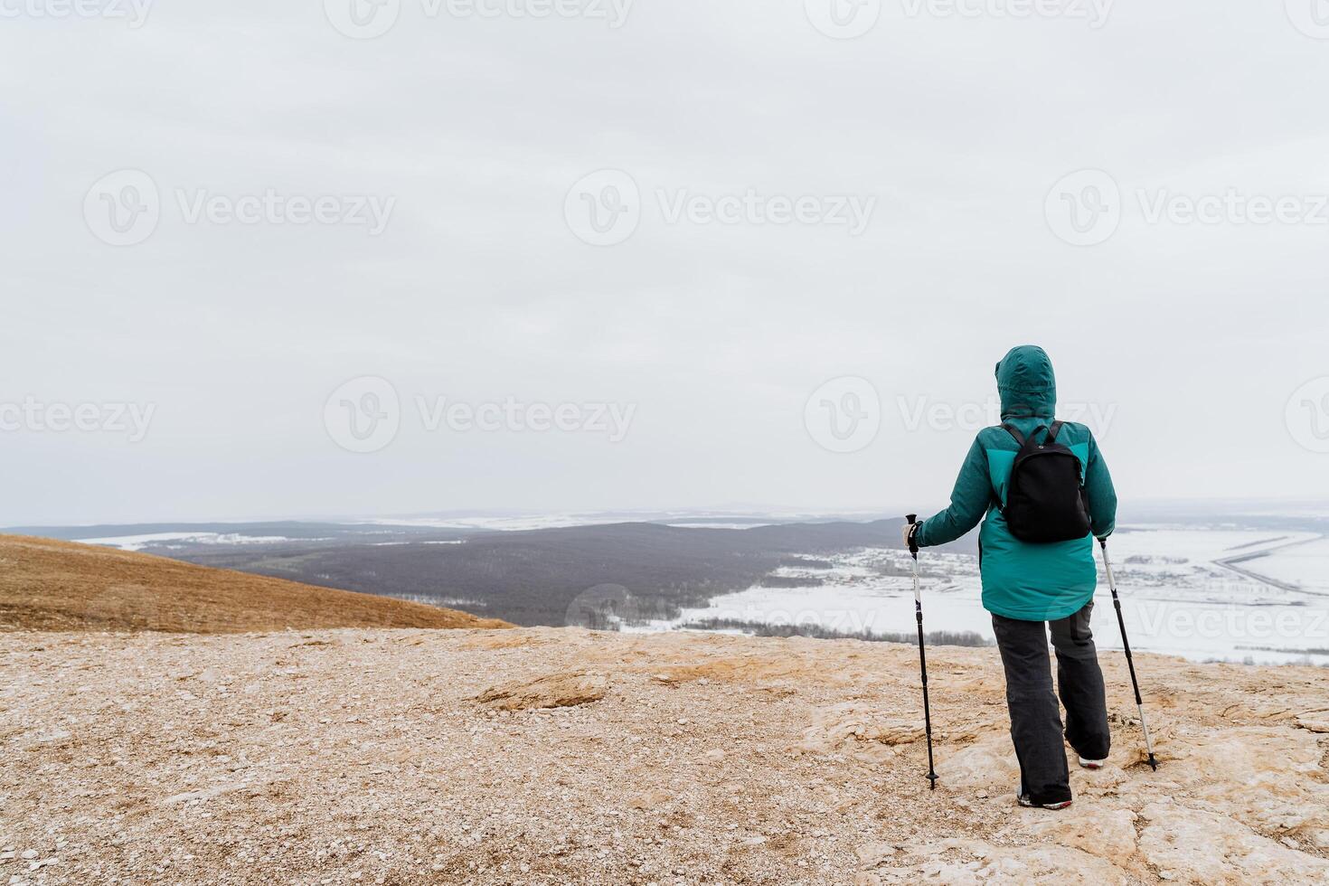 A man stands on top of the mountain Toratau Bashkortostan Russia Southern Urals, Nordic walking with sticks, spring hiking in the mountains, a beautiful view of the valley, a backpack on his back. photo