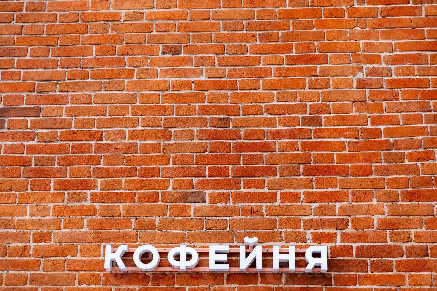 Minimalistic shot of a brick wall with sign. A coffee shop sign on the wall. Announcement on the facade of the building. Red brick masonry. photo