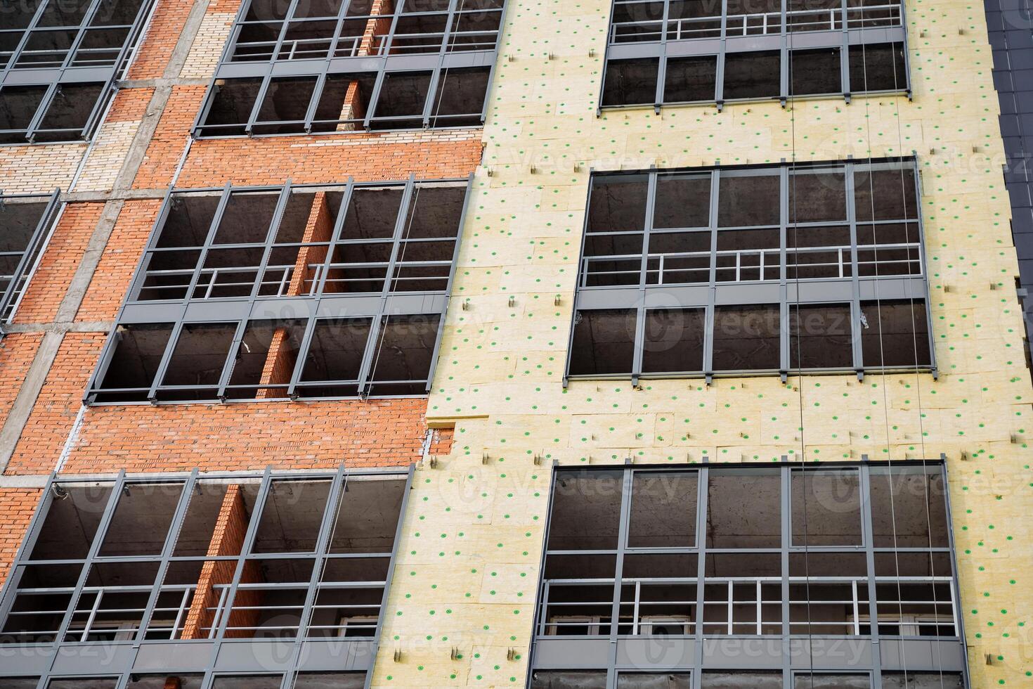 The fasade of the house can be seen with thermal insulation. yellow insulation should be mounted on the wall of the building. Metal aluminum profile for glass installation. photo