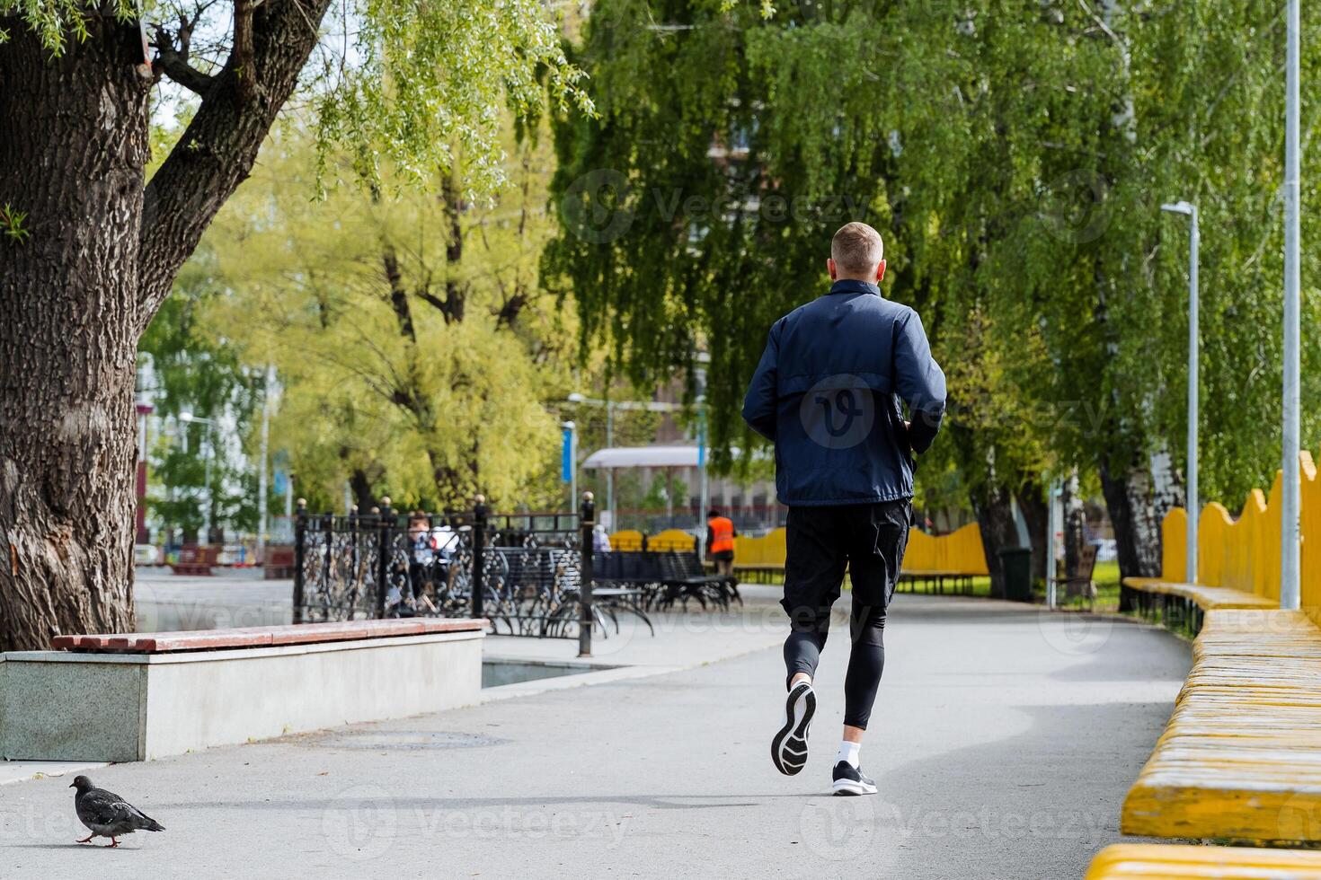 A man is engaged in sports running in a city park, a guy trains in the fresh air, vacations in the city, an active lifestyle, a charge of vivacity. photo
