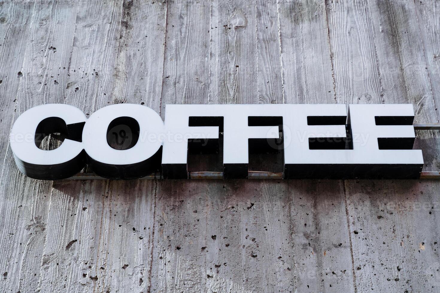 The sign is a coffee restaurant, the word hangs on the wall of the cafe, white printed letters, three-dimensional advertising symbols. photo