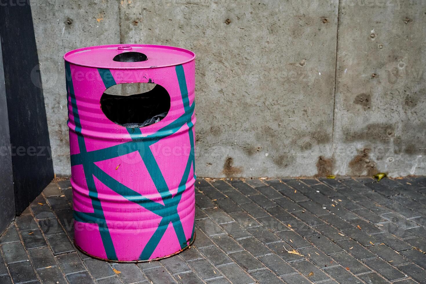 A pink trash can with a blue and green design photo
