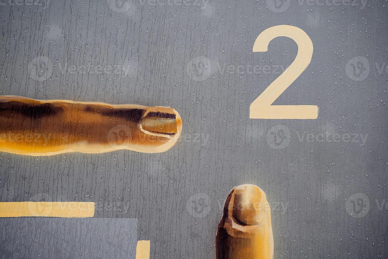 A hand is pointing to a number two on a wall photo