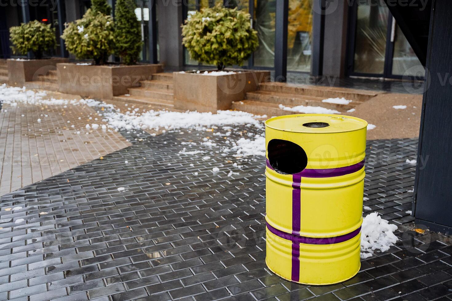 A yellow trash can sitting on a sidewalk photo