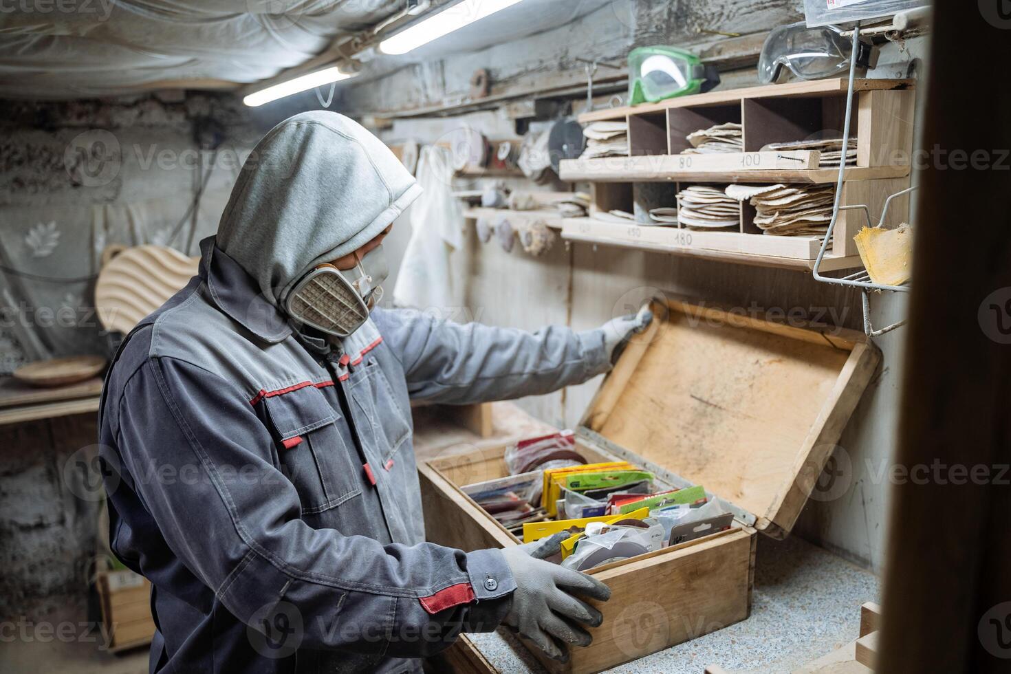 Joiner and his woodworking tools. Work in the workshop. Creation of household items from wood. Special clothes and gas mask at the carpenr photo