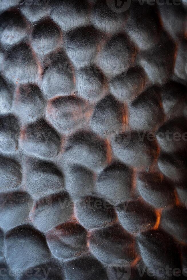 A close shot of the plate texture. Kitchen utensils made of natural material. Wooden plate of dark material with an unusual design. Made by a master of wood carving. photo