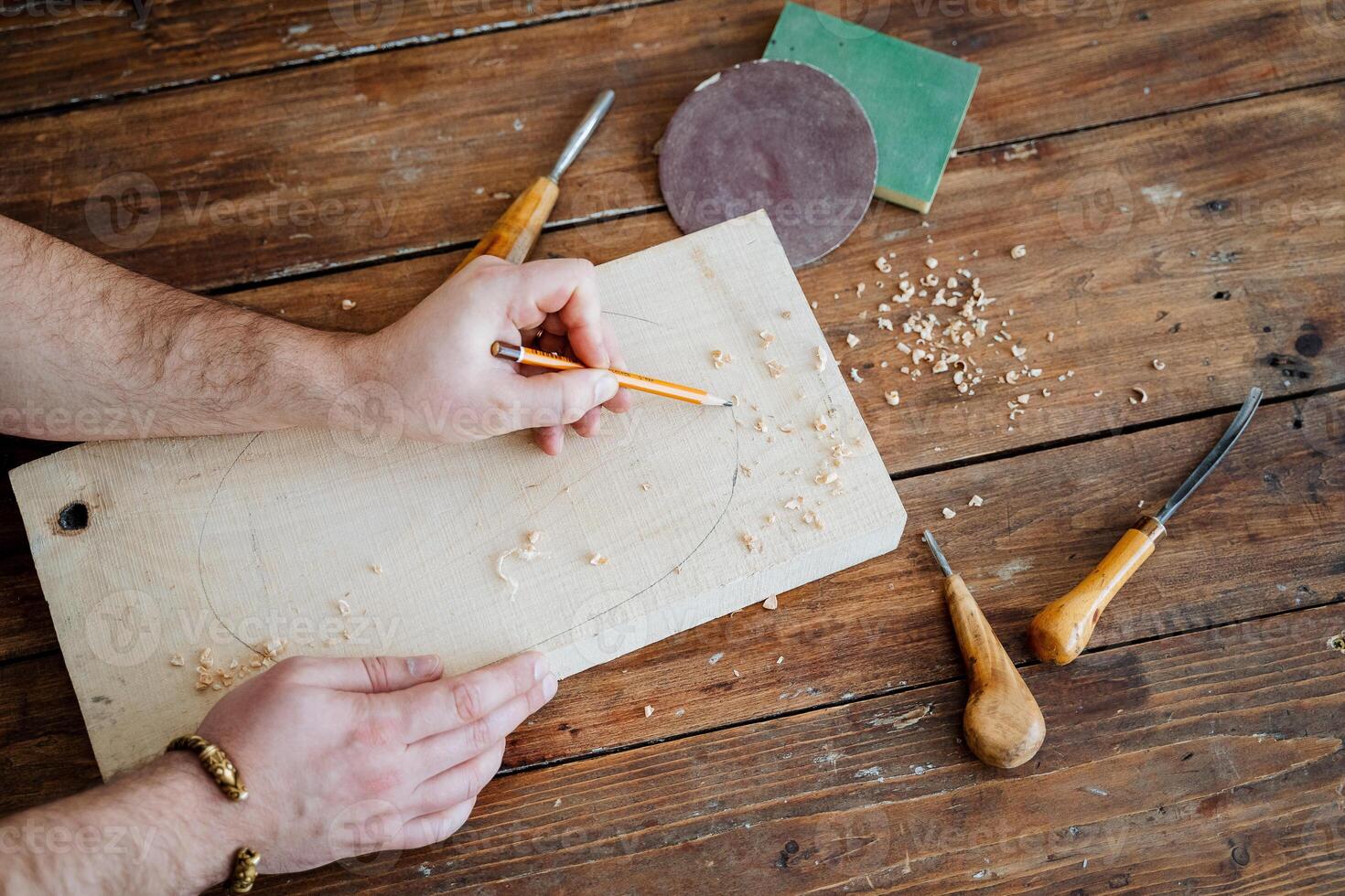 The carpenter draws with a pencil on the board. hand holds a pencil, carpentry workshop, sketch of the future product photo