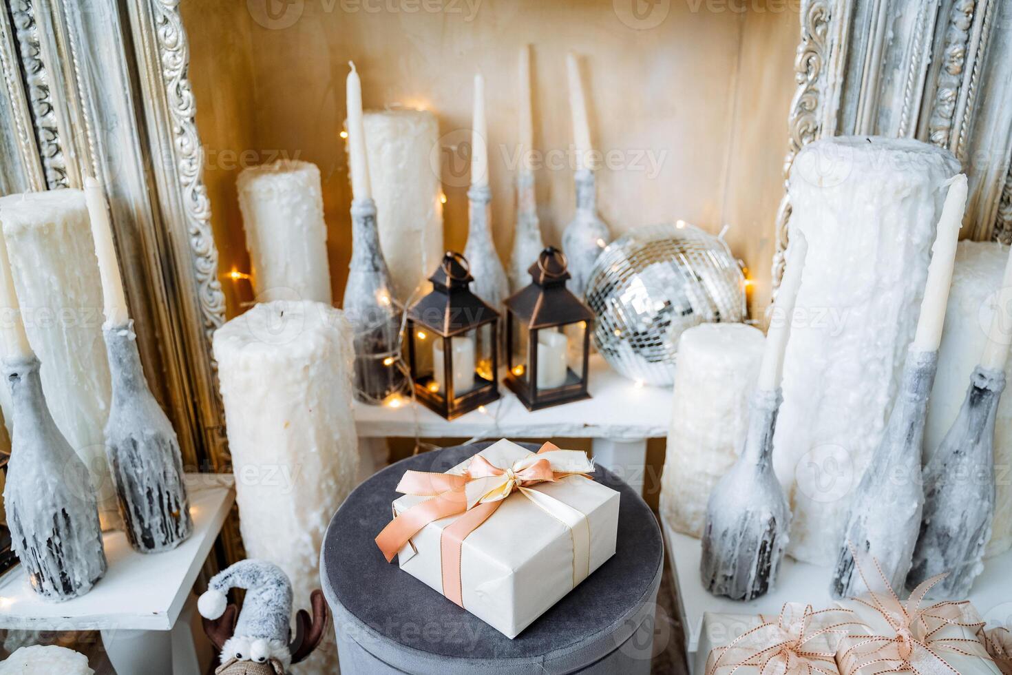 A big gift box with a lush bow on a festive background. Large candles and candlesticks around the gift.Christmas decorations and Christmas and New Year's mood. photo