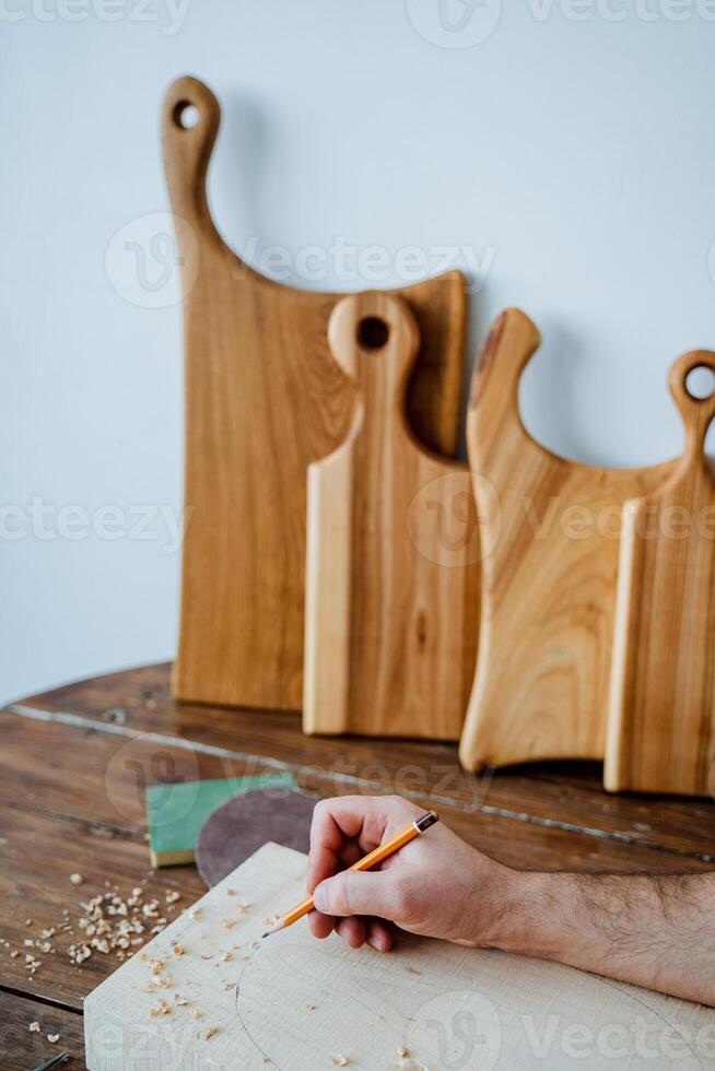 The carpenter draws with a pencil on the board. hand holds a pencil, carpentry workshop, sketch of the future product photo