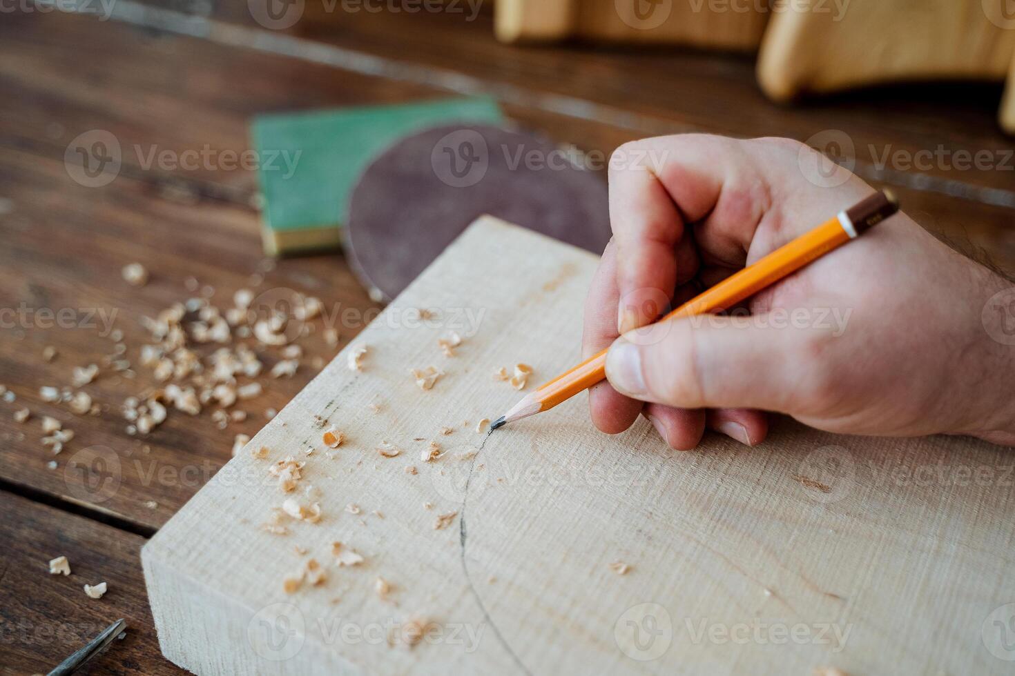 The carpenter draws with a pencil on the board. hand holds a pencil, carpentry workshop, sketch of the future product photo