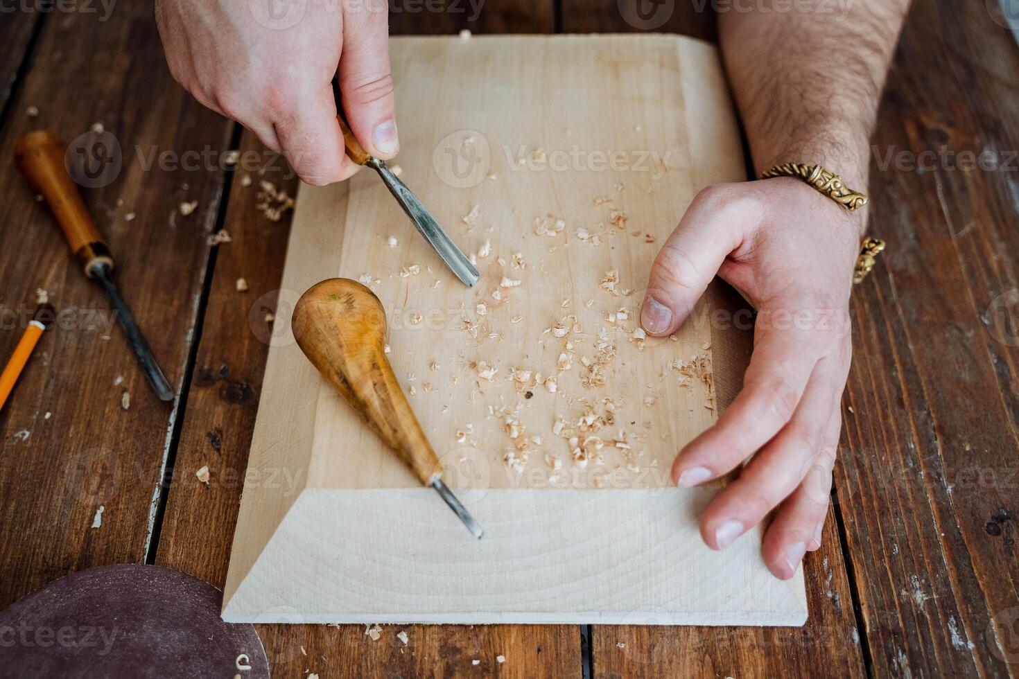 the carpenter's hands are cut with a tool on a board, a carpenter works in a workshop, a chisel in wood, sawdust photo