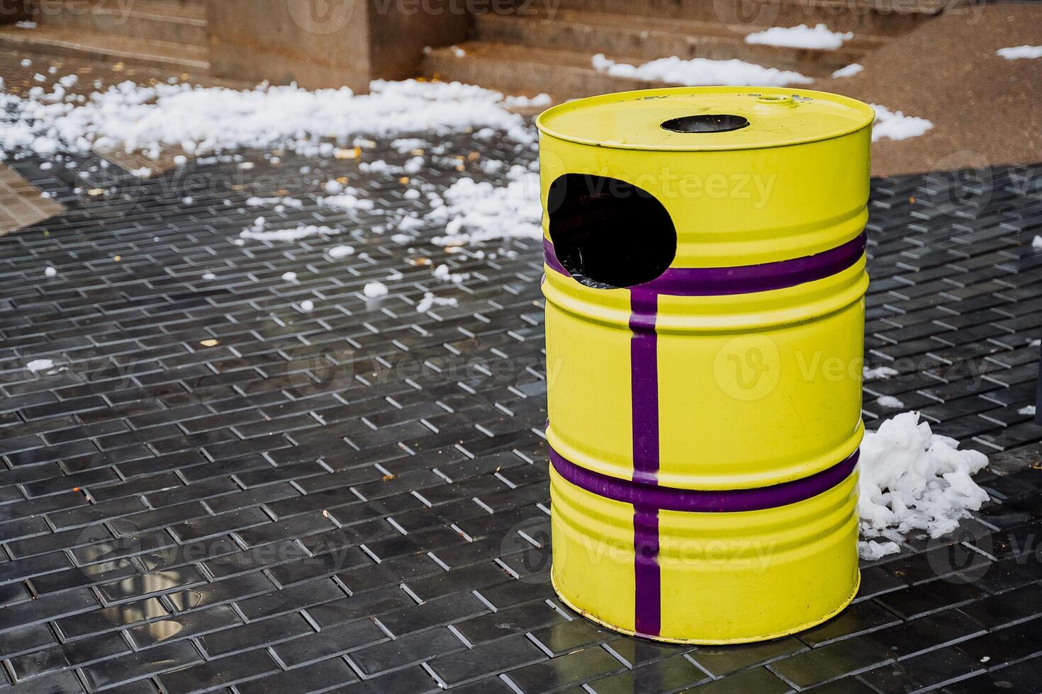 Yellow garbage can on the background of the city. The concept of cleaning and ecology. Round barrel for garbage collection photo
