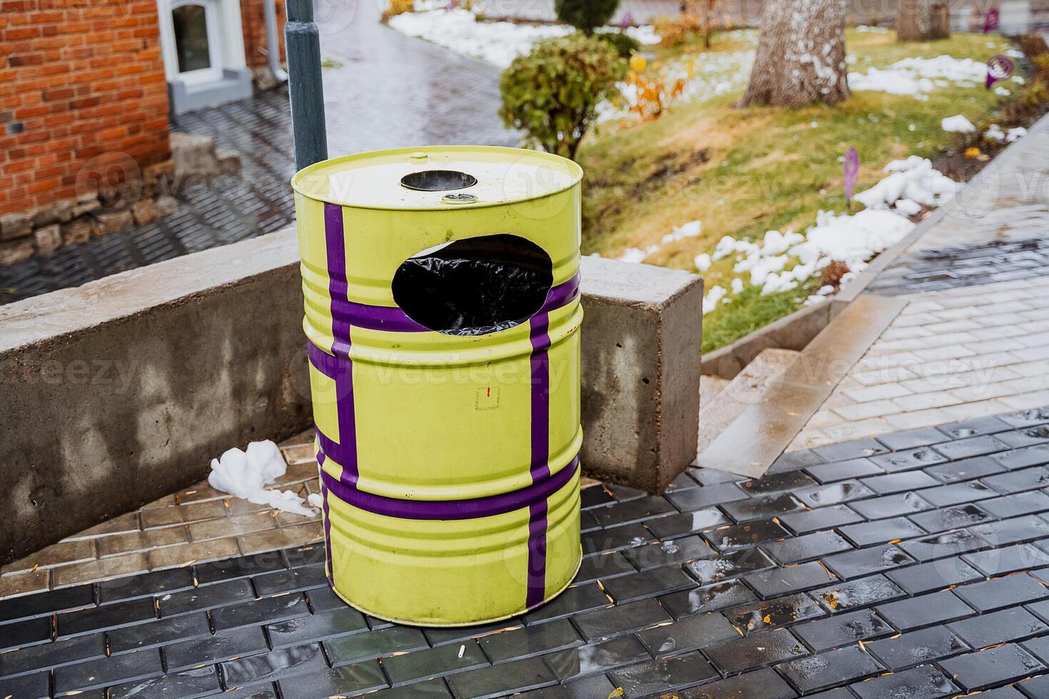 Yellow garbage can on the background of the city. The concept of cleaning and ecology. Round barrel for garbage collection photo