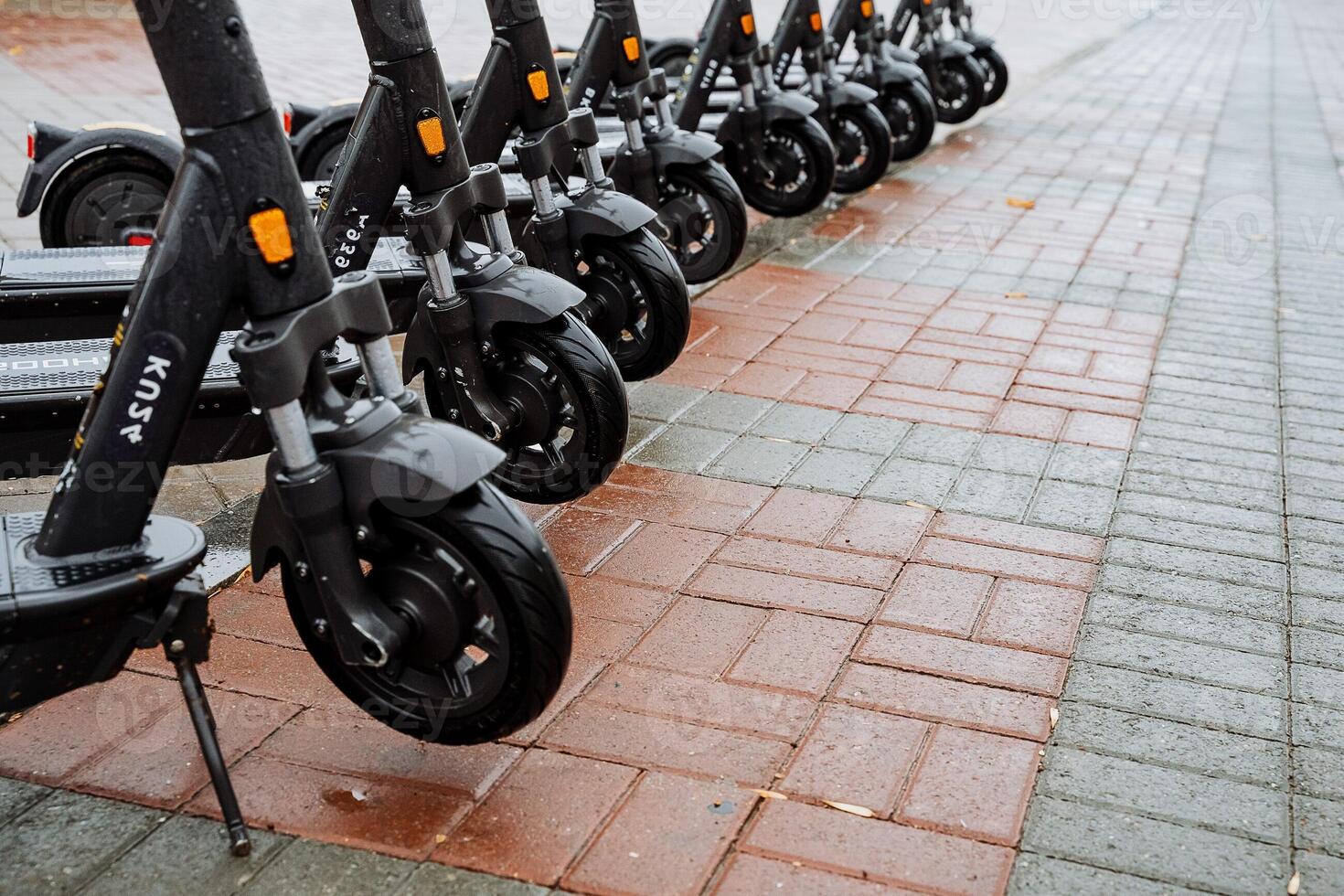 Parking of electric scooters on the street. The wheels of the scooter are in a row. The concept of eclogical transport. Black color of scooter photo