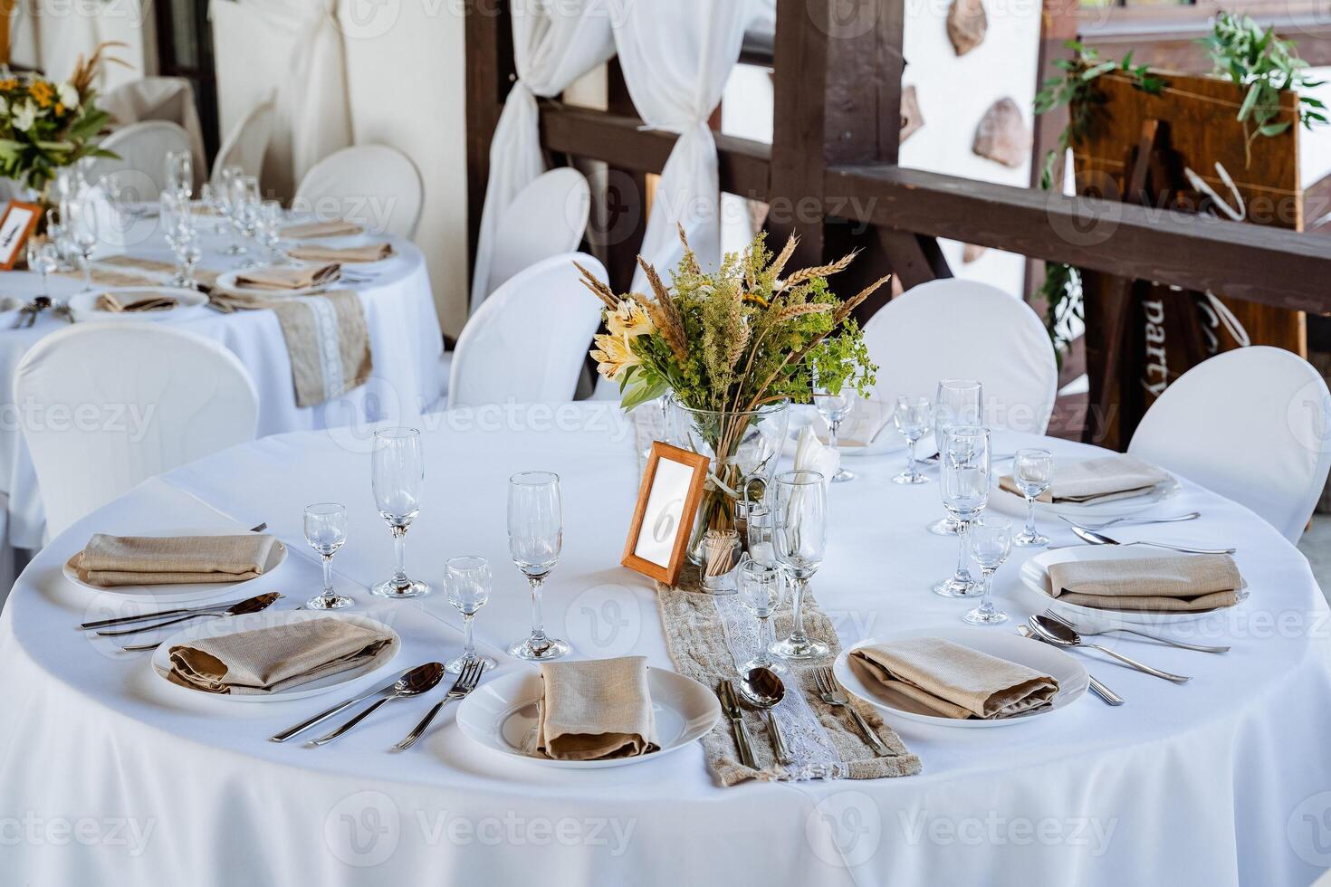 Serving a festive table, placing plates on the table, a Banquet table with a white tablecloth, preparing the dining table for the holiday, Cutlery is arranged according to etiquette. flowers on the photo