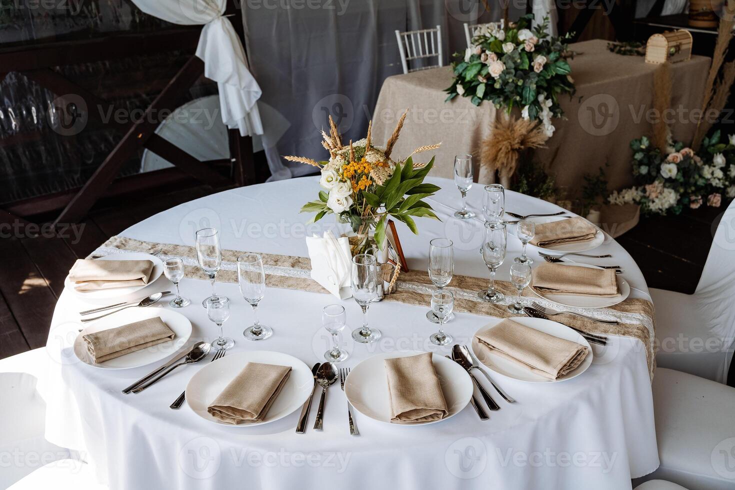 Serving a festive table, placing plates on the table, a Banquet table with a white tablecloth, preparing the dining table for the holiday, Cutlery is arranged according to etiquette. flowers on the photo