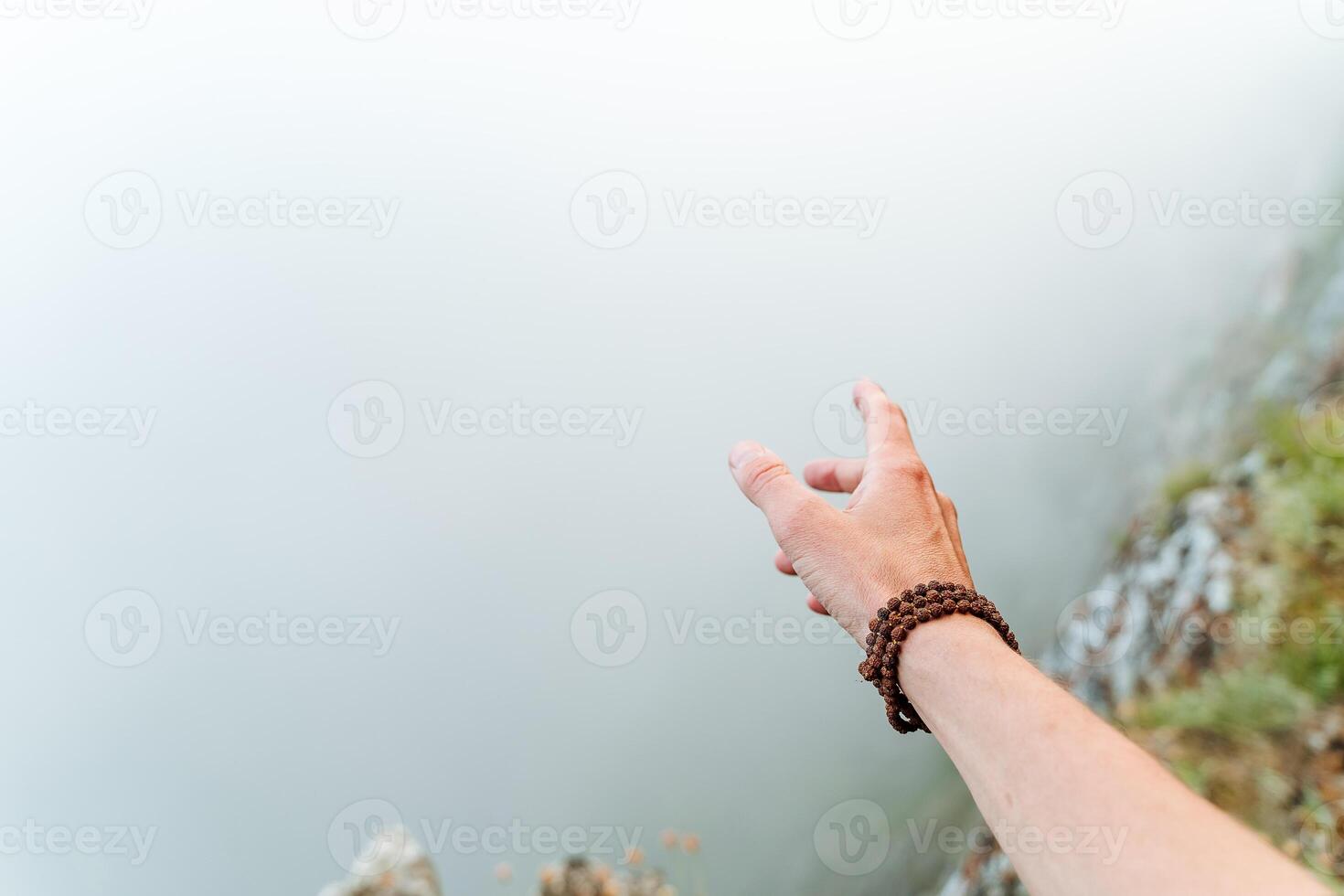 hand with a Rudraksha bracelet on the background of fog, fog in the mountains, morning photo