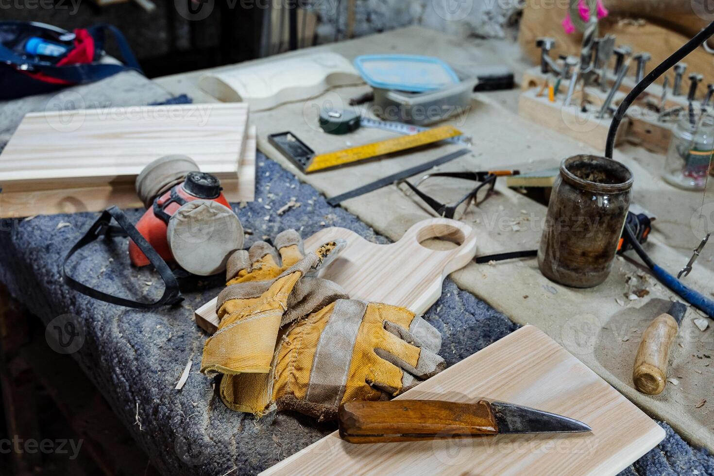 carpentry workshop with tools for woodworking, workbench for working with boards, dust mask and leather gloves, a set of wooden blanks for cutting boards, shop photo