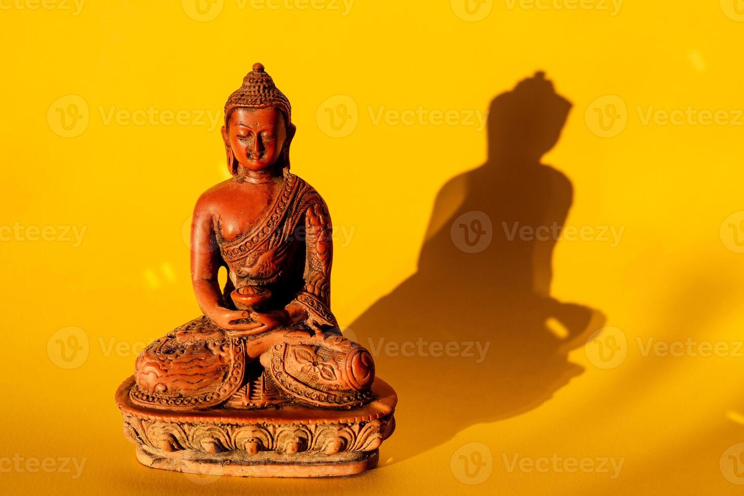 Buddha on a yellow background. figurine of a Buddha statue brown. jade Buddha, meditation, yoga photo