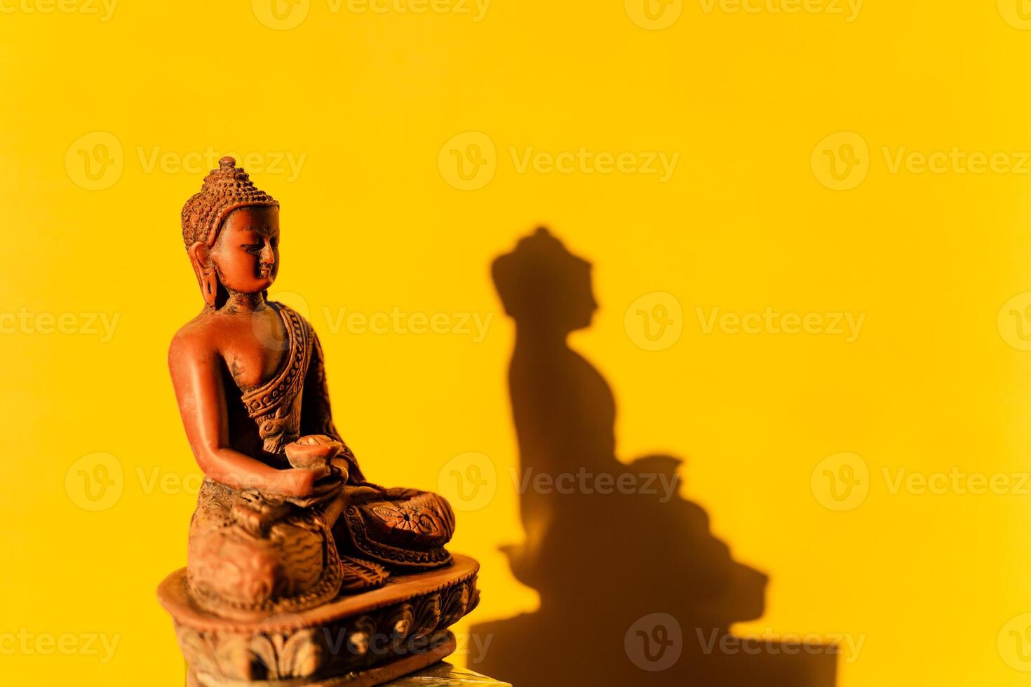 jade Buddha, Buddha figurine on a yellow background, shadow of the Buddha in the sun photo