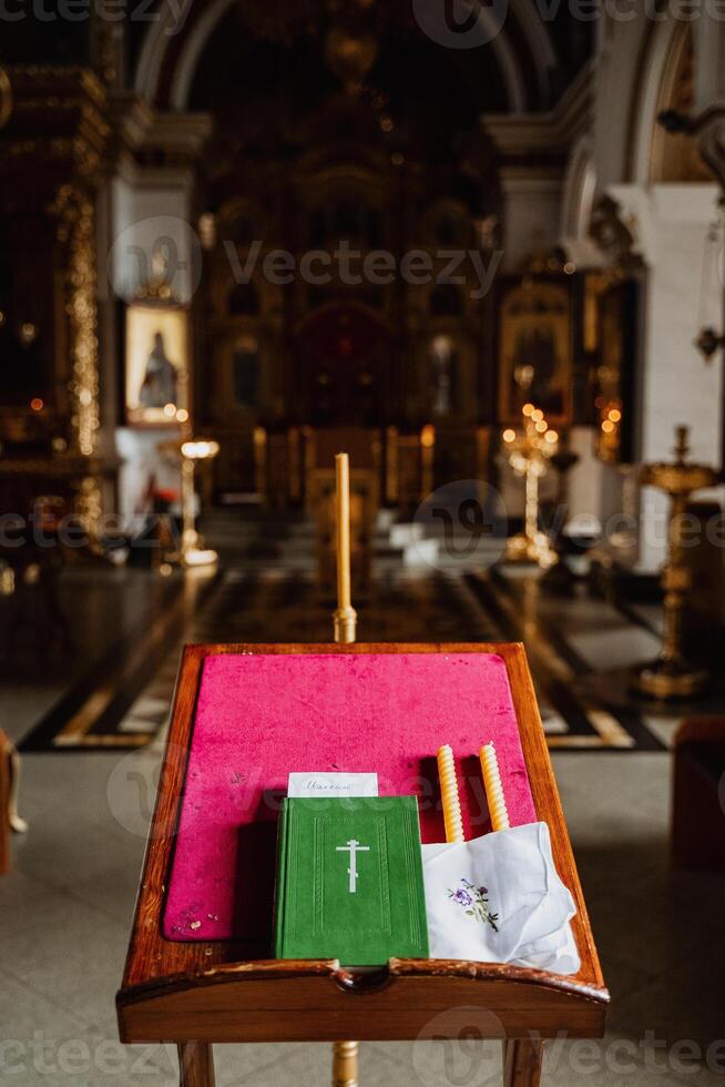 Church book the Bible is on the table in the temple, items for the wedding ceremony, candles, cross, close-up photo