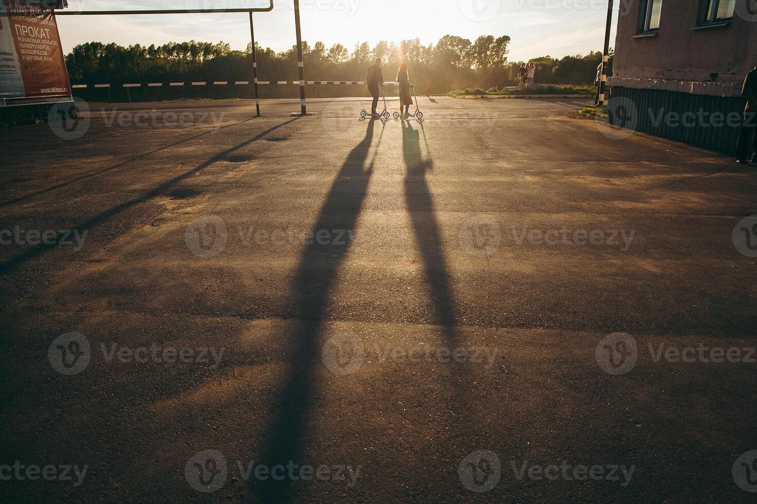 To ride a skateboard at sunset. Young people ride a scooter. Actively spend time together. photo