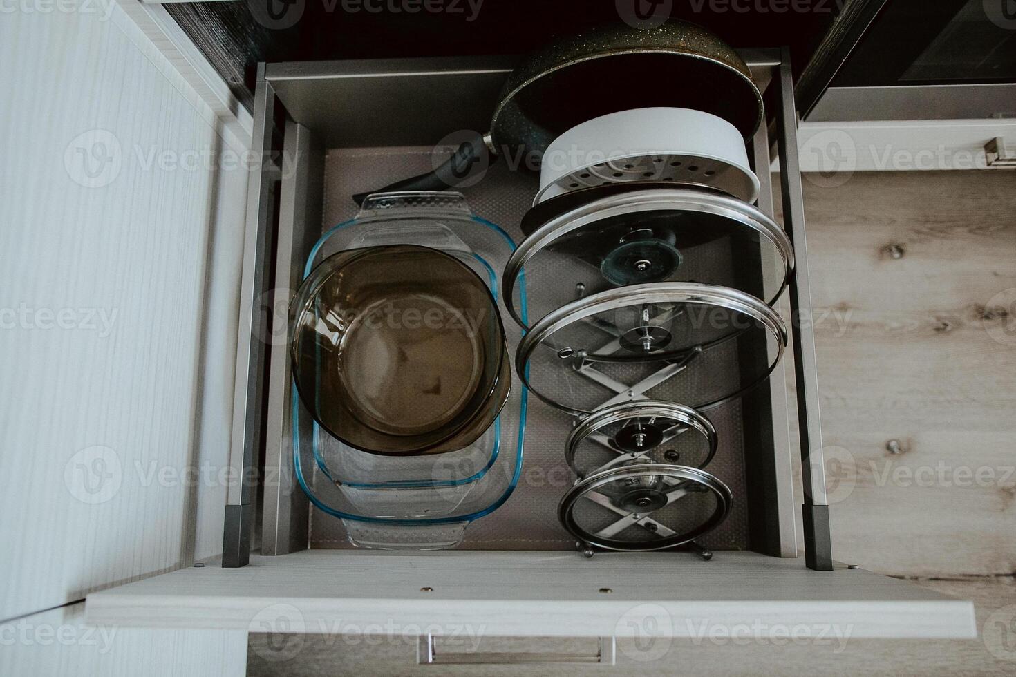 Order in the kitchen. Dishes in the kitchen are in a drawer. Arrange the plates and lids in their places. photo