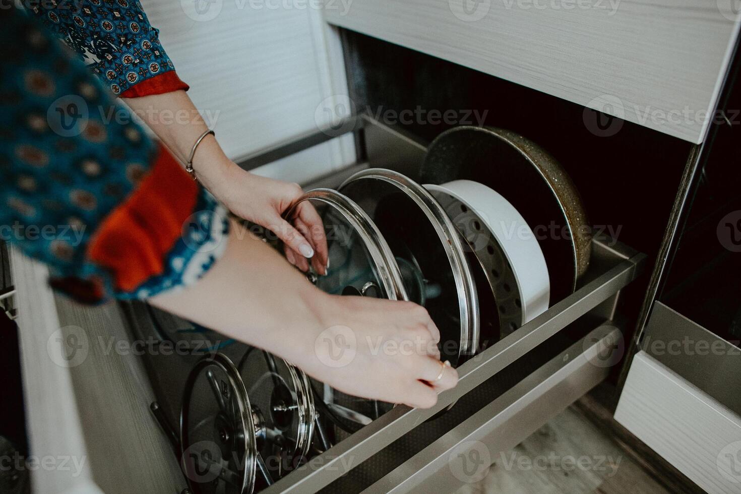 Order in the kitchen. Dishes in the kitchen are in a drawer. Arrange the plates and lids in their places. photo