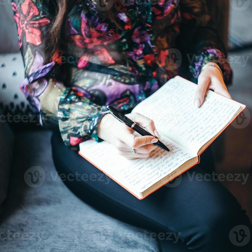 write business ideas in a notebook, a girl sitting in a cafe writes with a pen in a notebook, near the window, transfer thoughts to paper photo