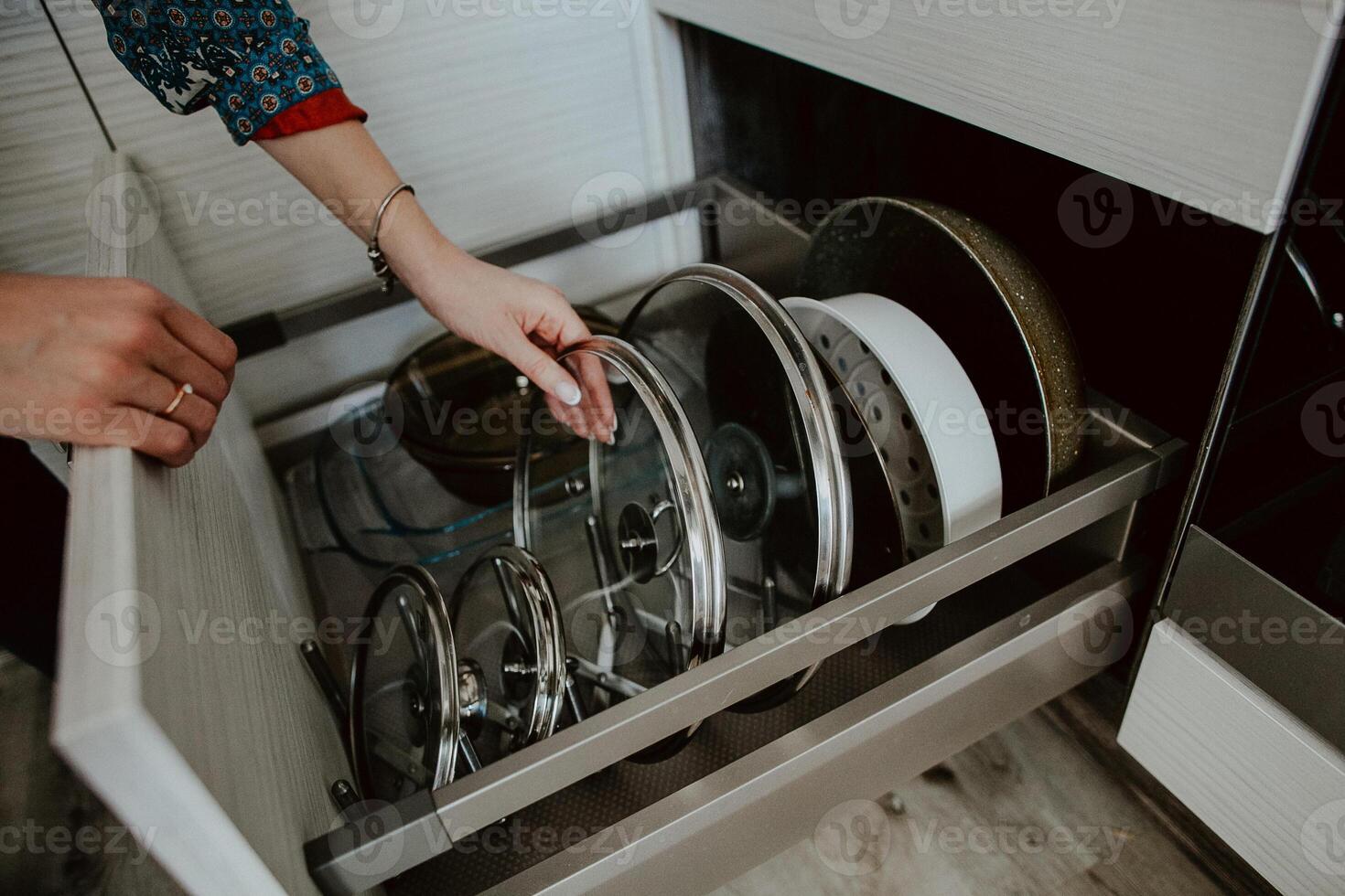 Order in the kitchen. Dishes in the kitchen are in a drawer. Arrange the plates and lids in their places. photo