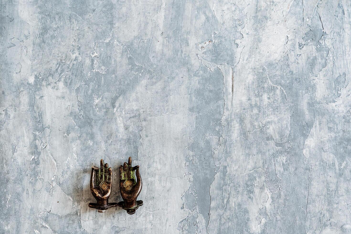 metal door handles in the shape of hands folded in mudra, shot on a textured gray background, close-up, separate object, yoga theme, bronze shade, Indian motif photo