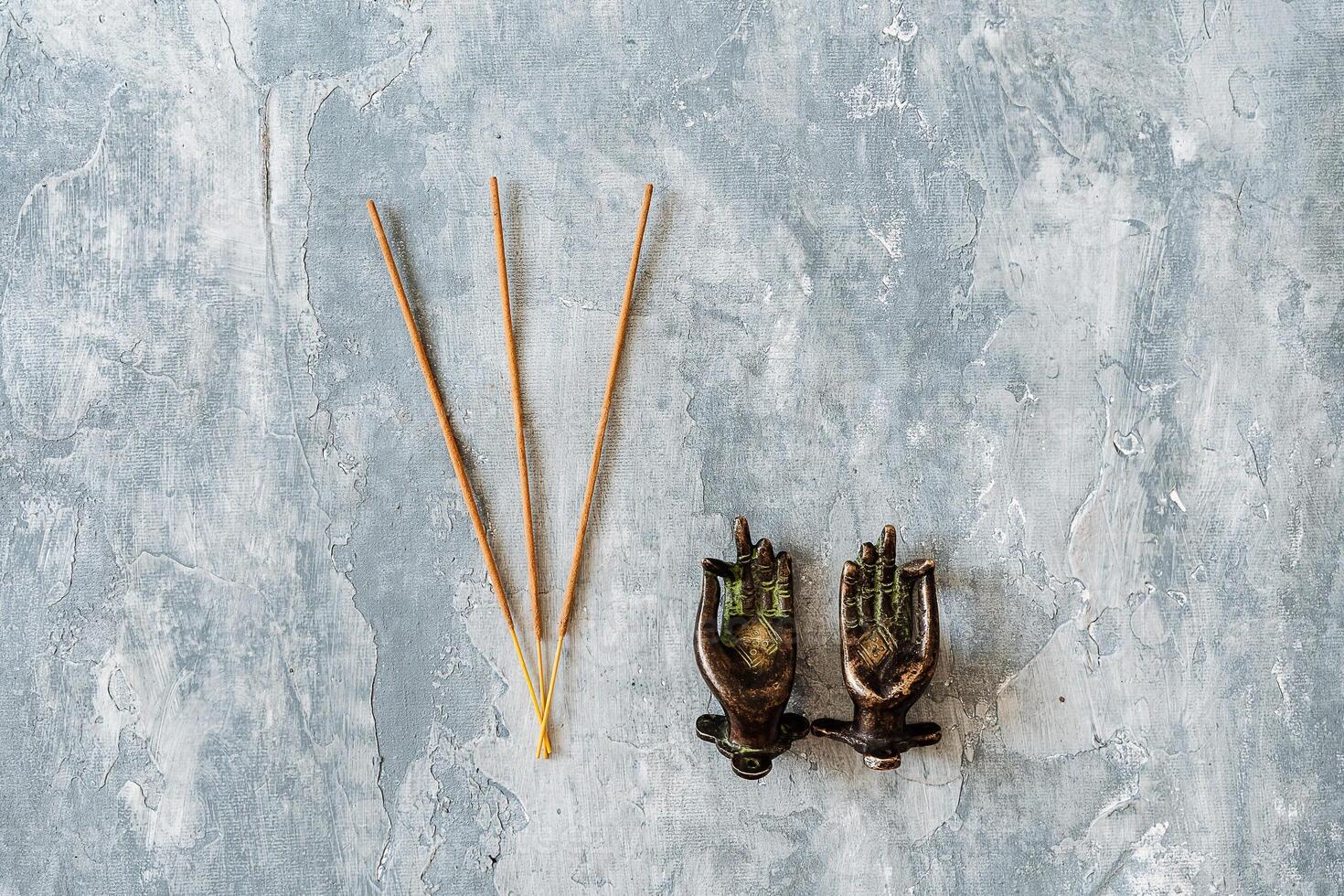 metal door handles in the shape of hands folded in mudra, shot on a textured gray background, close-up, separate object, yoga theme, bronze hue, Indian motif, incense photo
