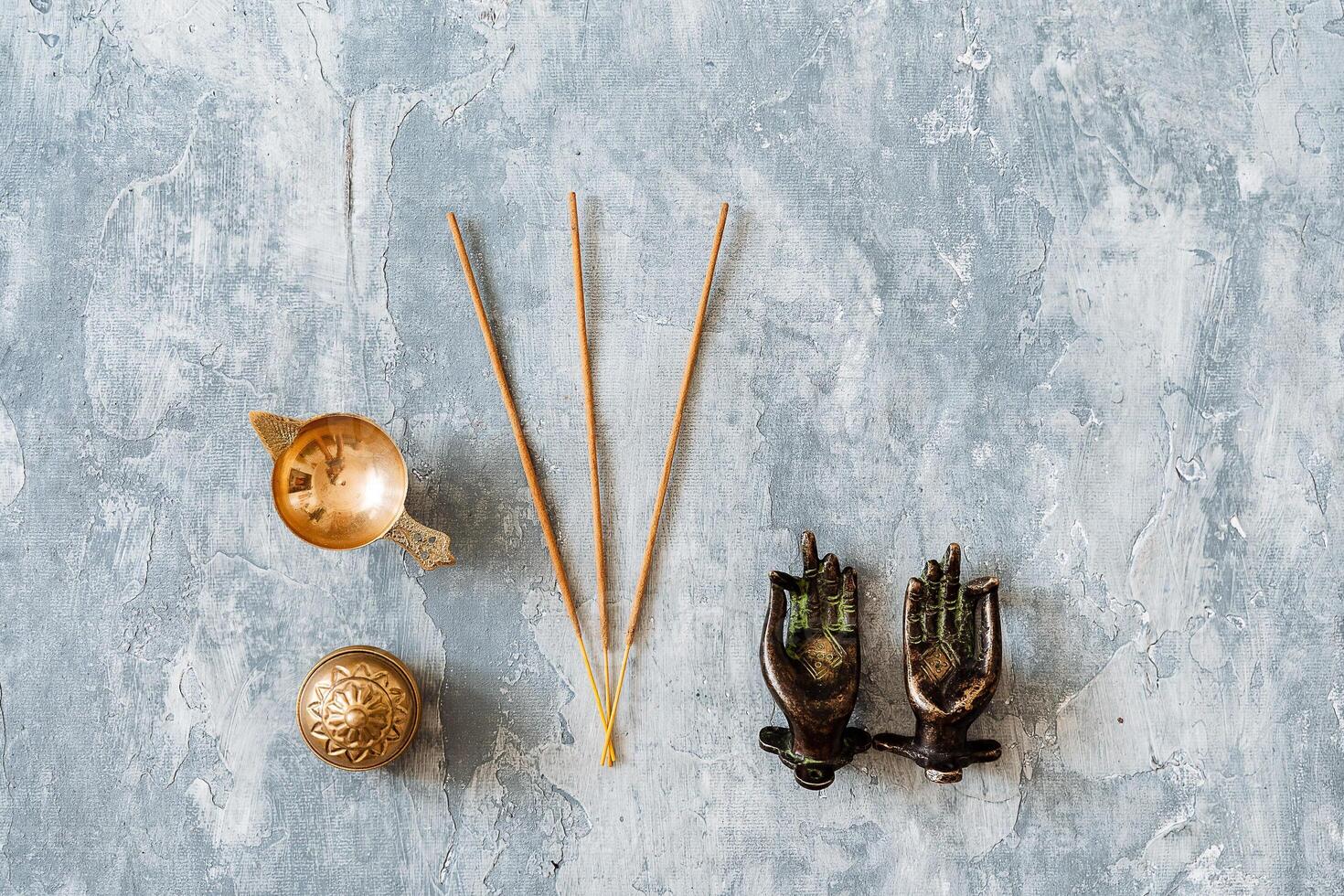 metal door handles in the shape of hands folded in mudra, shot on a textured gray background, close-up, separate object, yoga theme, bronze hue, Indian motif, incense photo