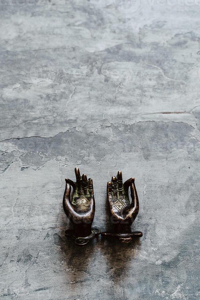 metal door handles in the shape of hands folded in mudra, shot on a textured gray background, close-up, separate object, yoga theme, bronze shade, Indian motif photo