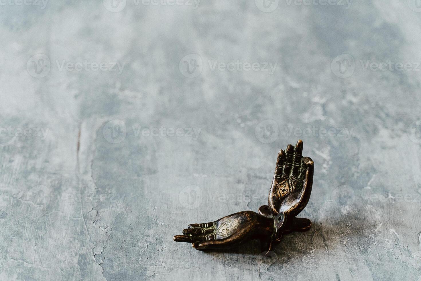 metal door handles in the shape of hands folded in mudra, shot on a textured gray background, close-up, separate object, yoga theme, bronze shade, Indian motif photo