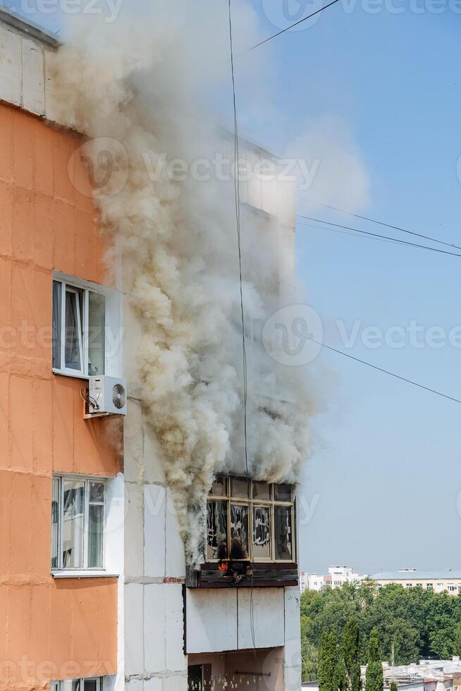 fire on the balcony of a multi-storey building, black clouds of smoke, apartment smoke, extinguishing fire in a residential building, fire escape, emergency photo