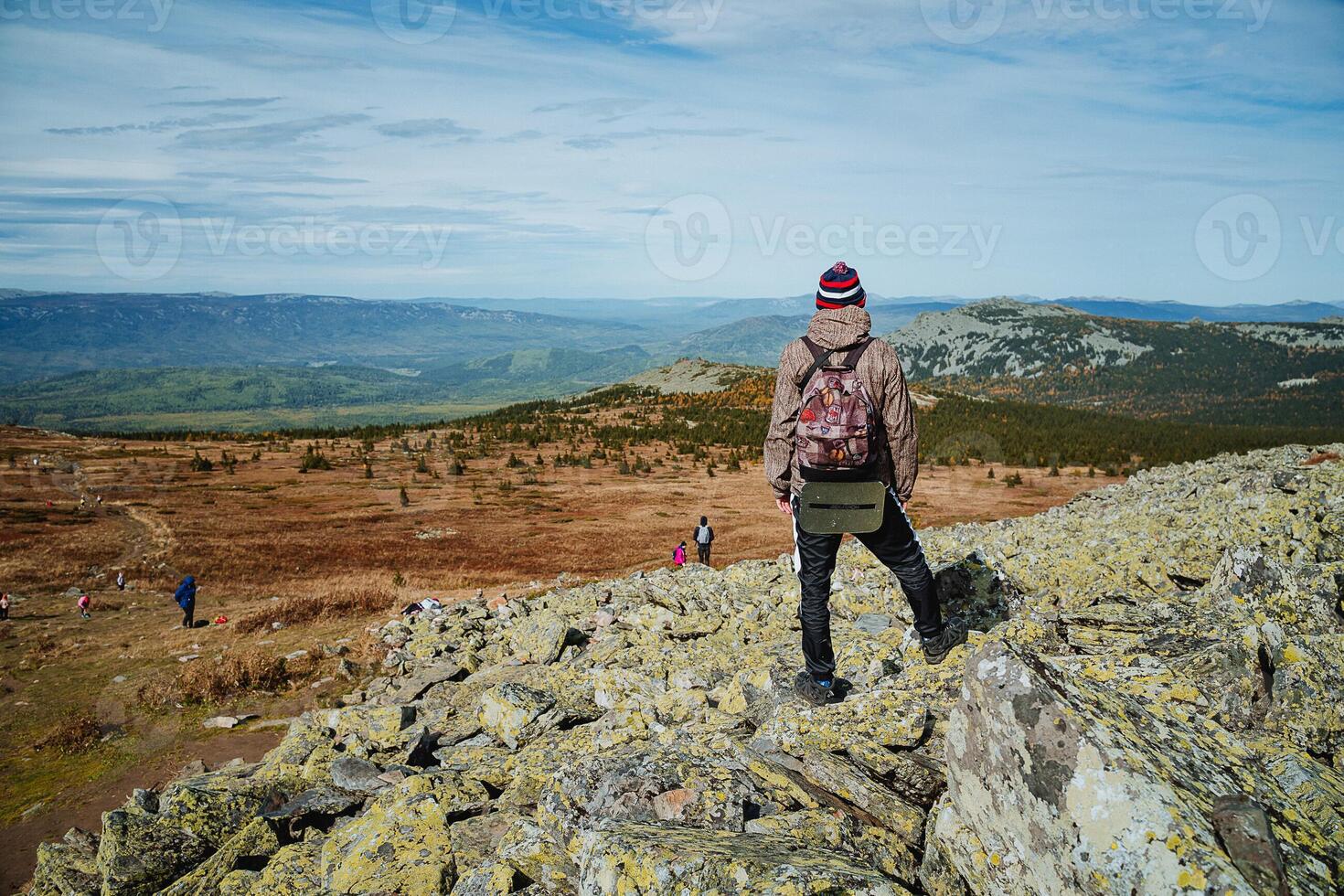 A person standing on a rocky hill with a backpack photo