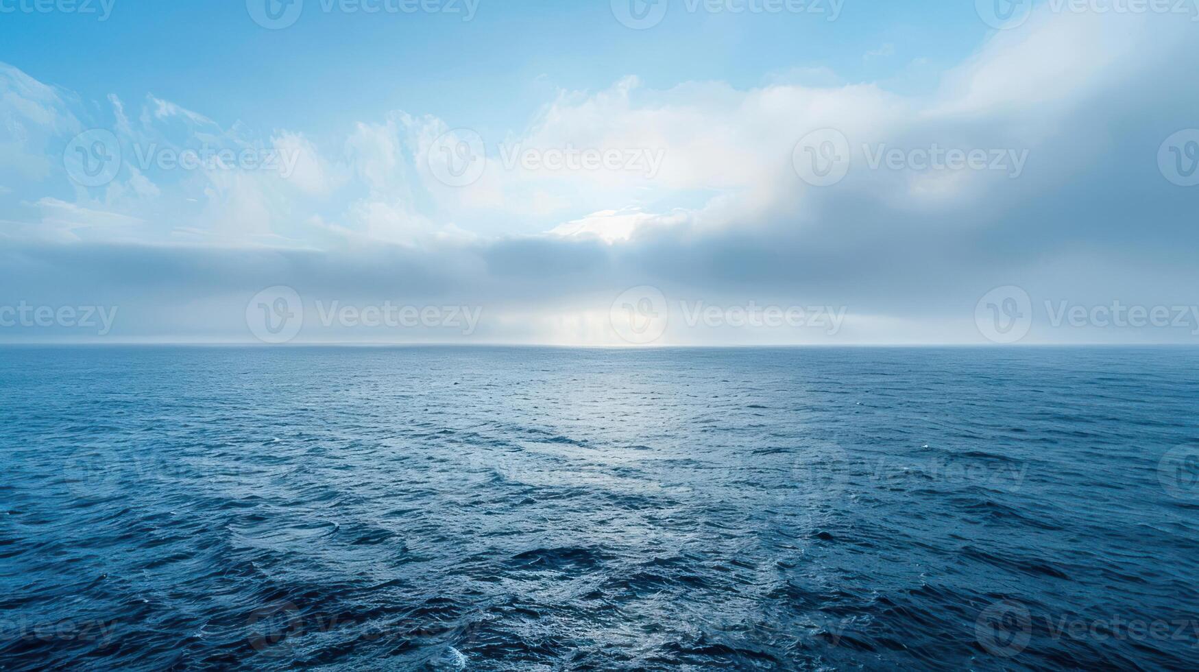 A vast expanse of blue ocean stretches to the horizon under a sky filled with fluffy white clouds. photo