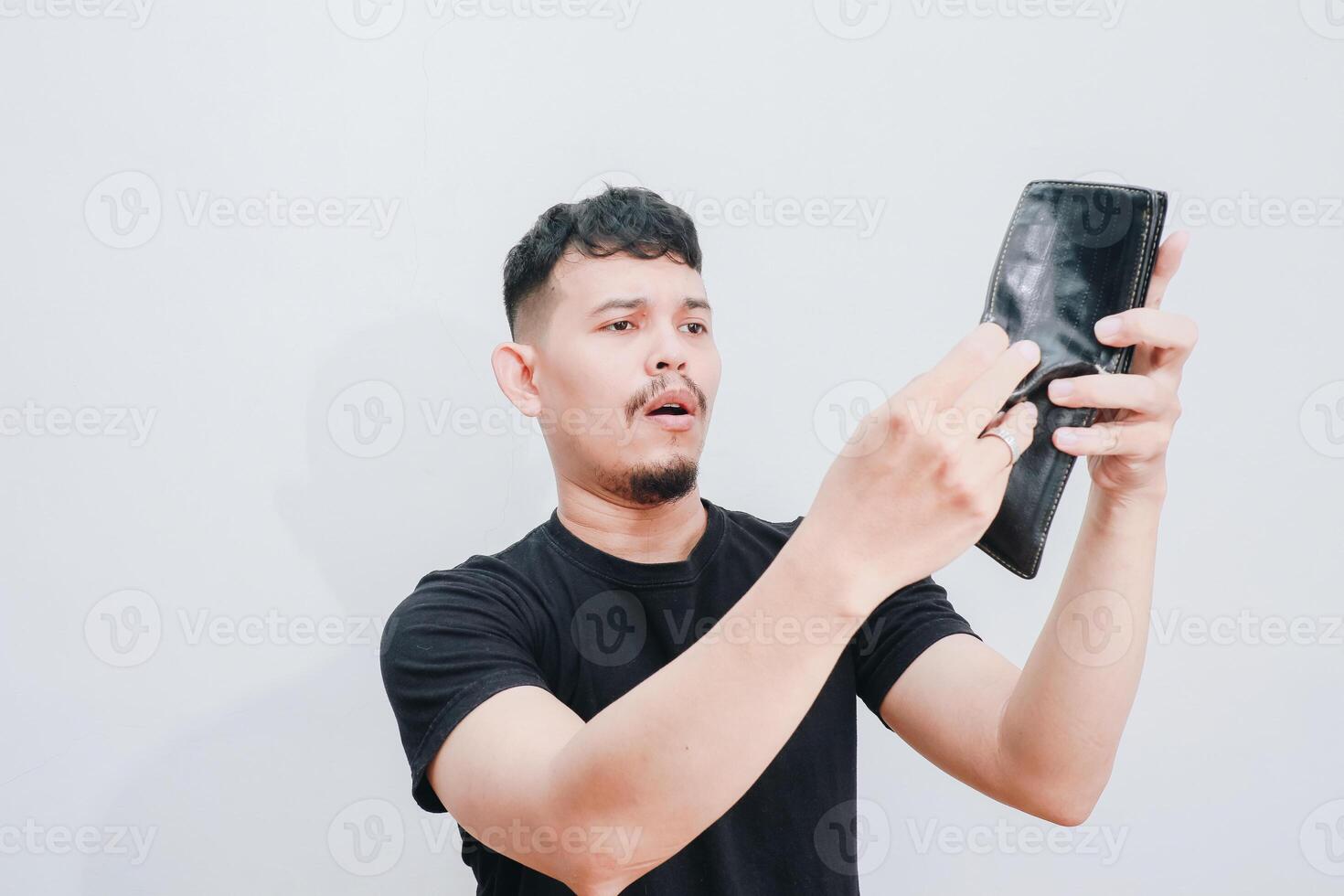 a portrait of asian young man holding his empty wallet with sad expression photo