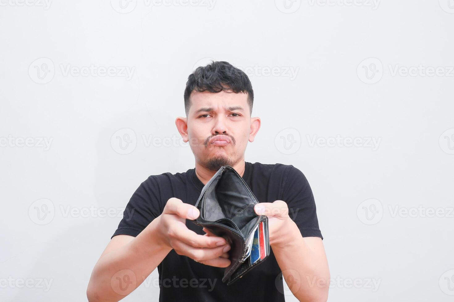a portrait of asian young man holding his empty wallet with sad expression photo