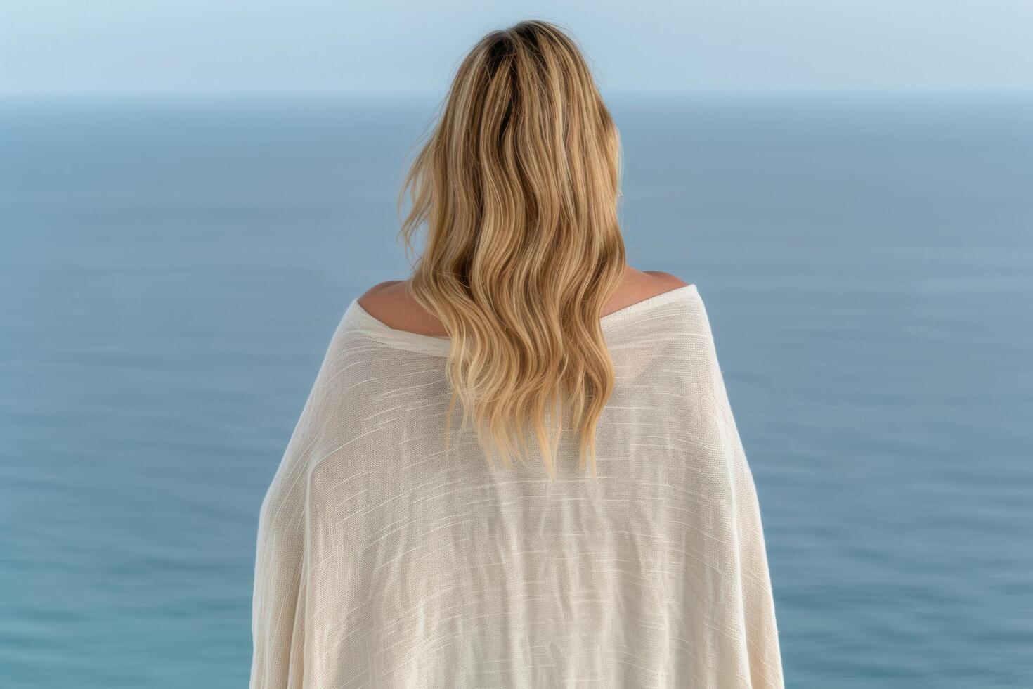 woman with long blonde hair looking out at the ocean photo