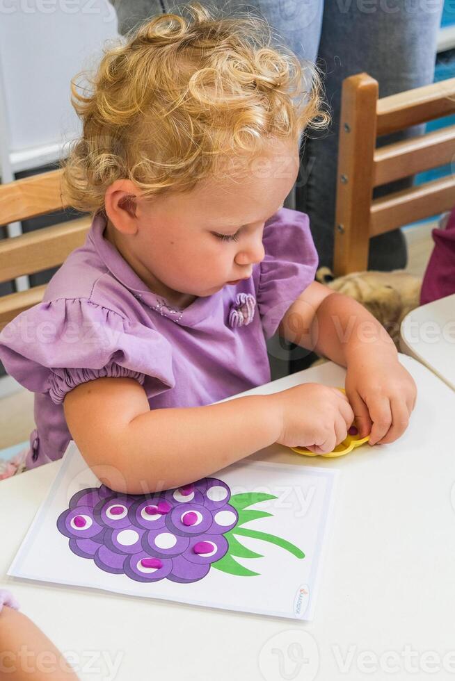 A child collects a puzzle for the development of fine motor skills photo