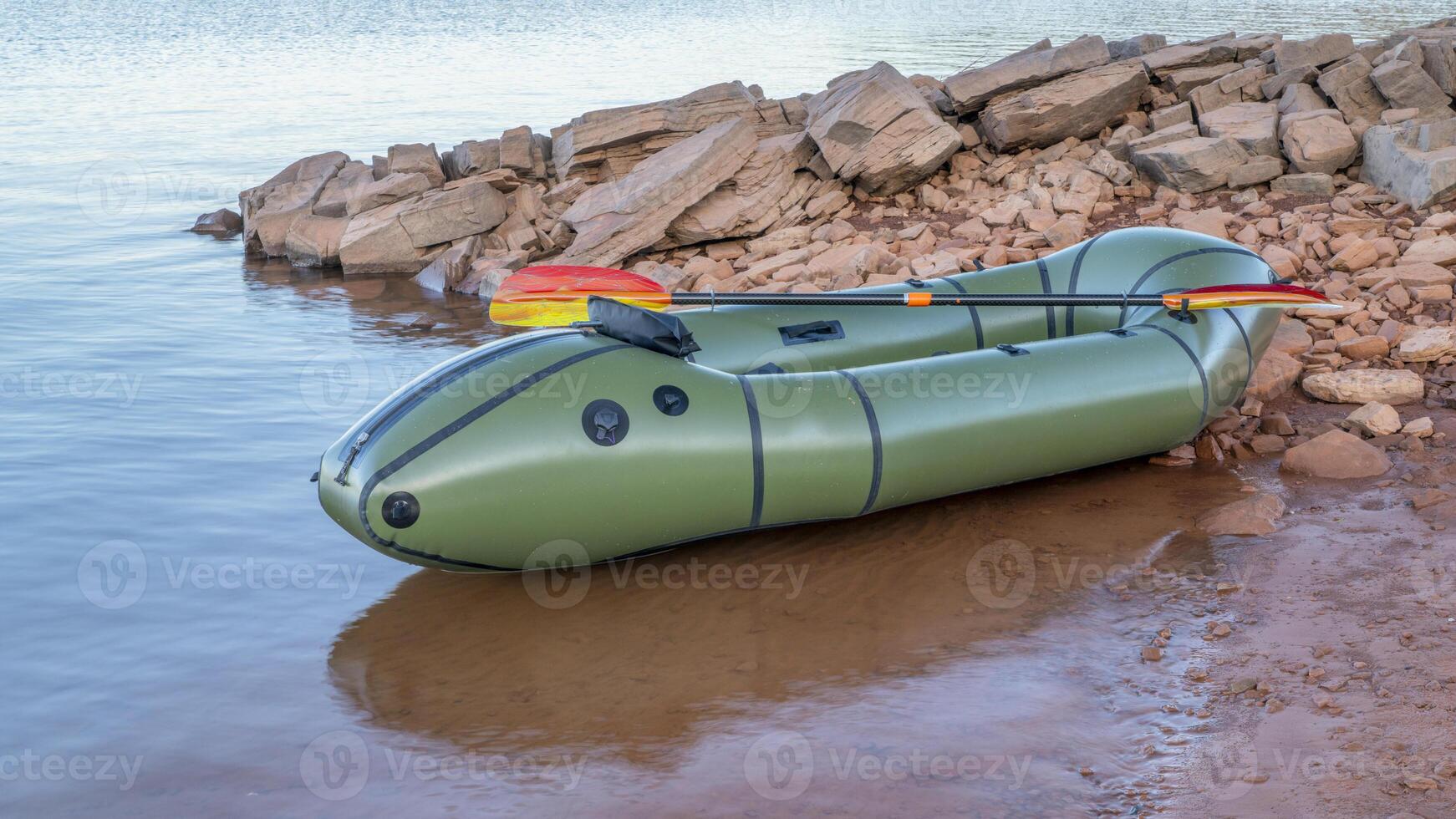 inflatable packraft, one-person light raft used for expedition or adventure racing, with a paddle on a lake shore in Colorado, on Horsetooth Reservoir photo