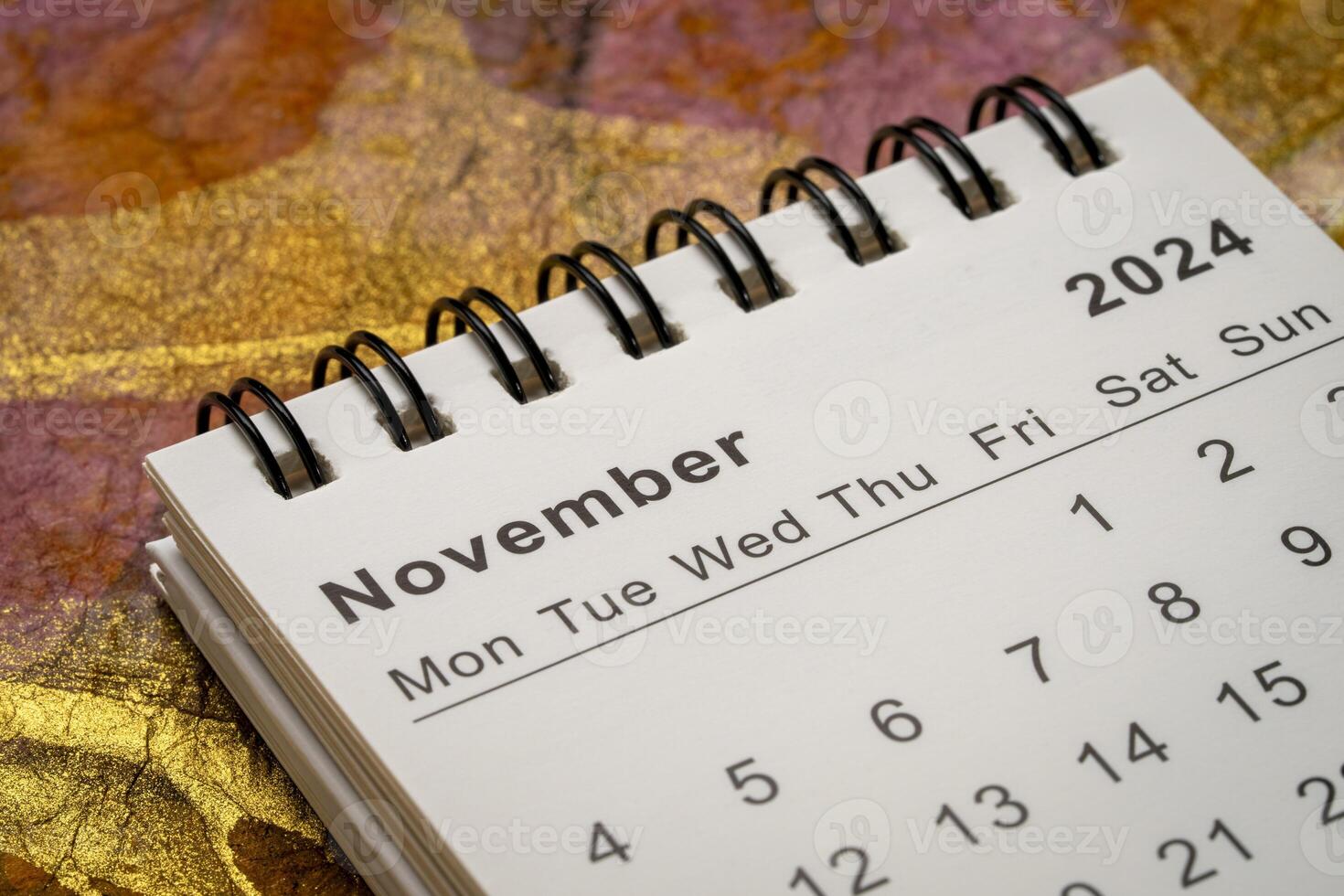 November 2024 - small spiral desktop calendar against abstract marbled paper, time and business concept photo
