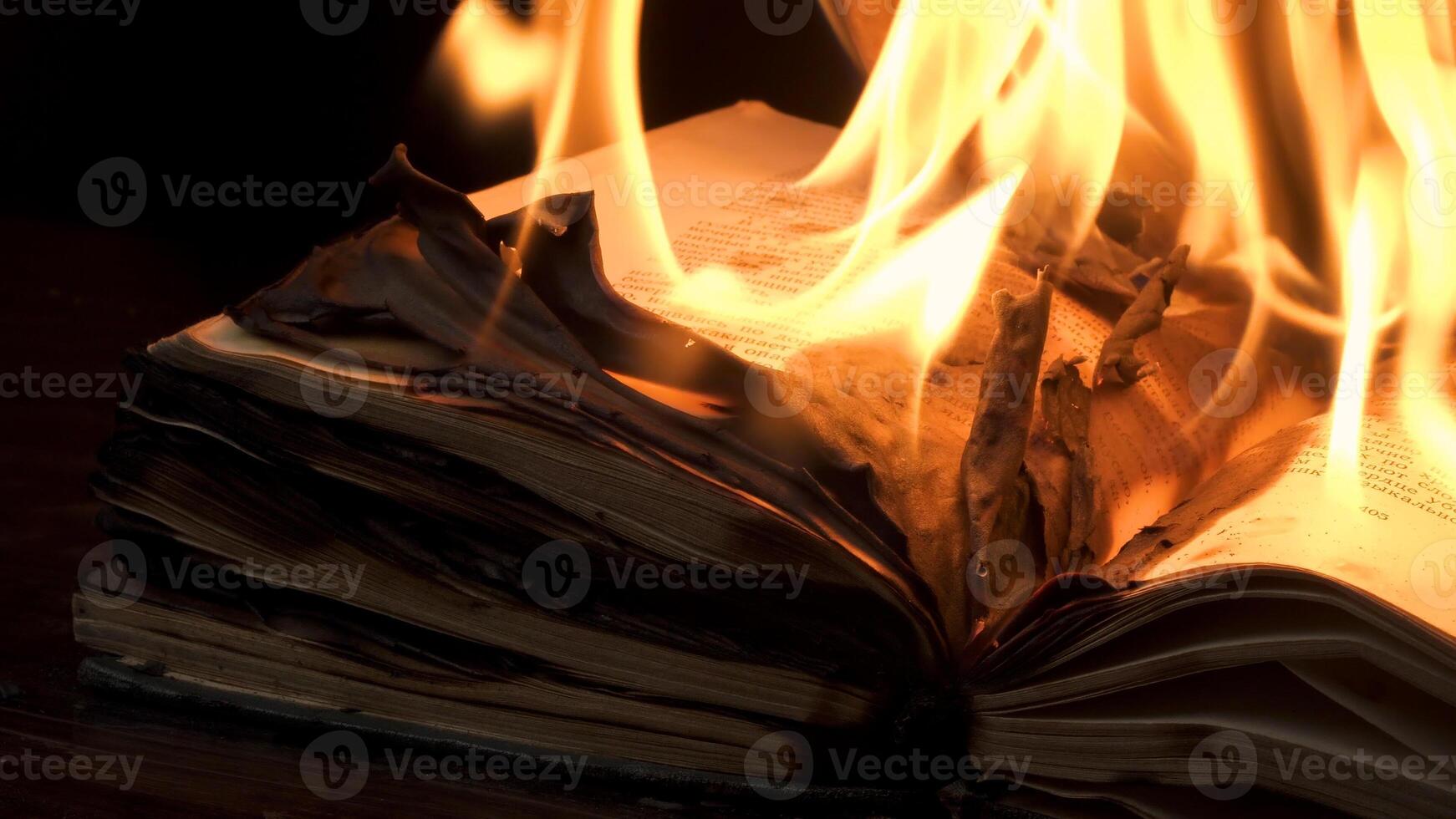 An open book is on fire. Big bright flame, burning paper on old publication in the dark. Book Burning - Censorship Concept photo