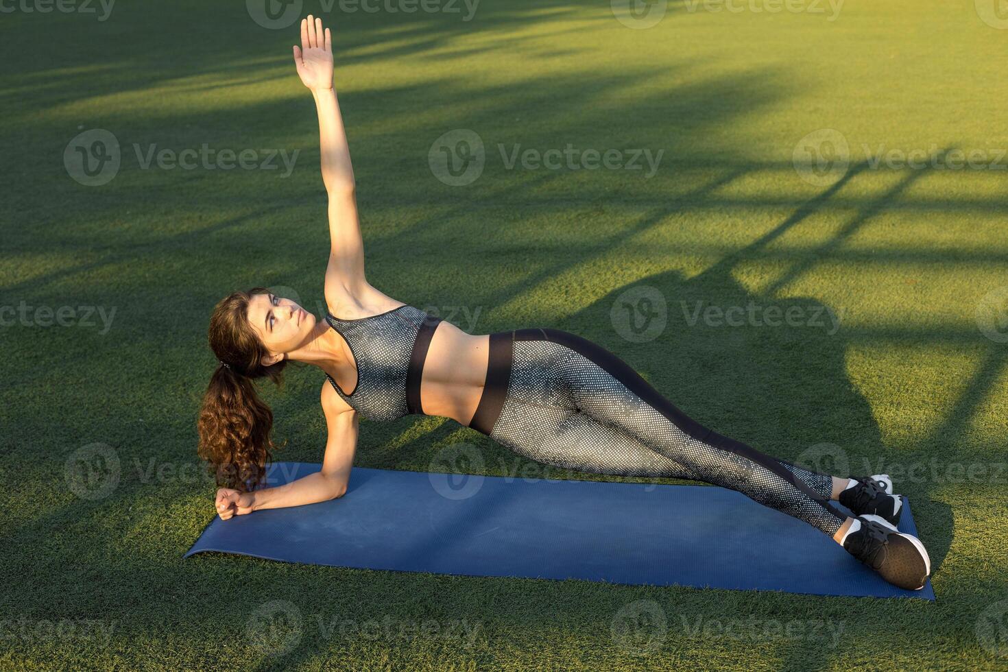 A young slim athletic girl in sportswear with snakeskin prints performs a set of exercises. Fitness and healthy lifestyle. photo