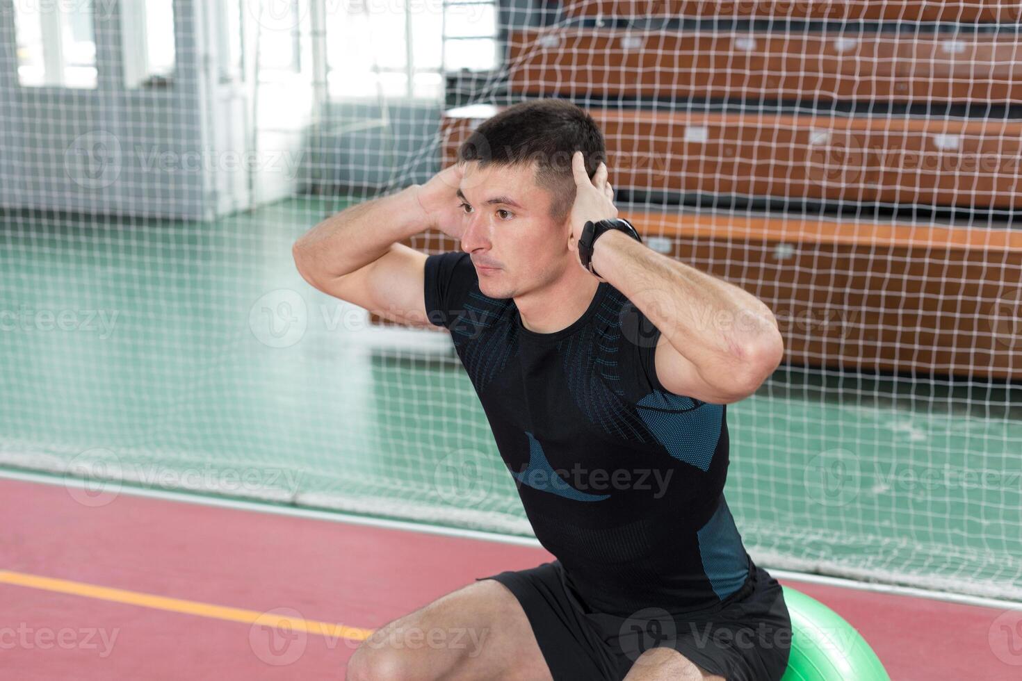 Athletic guy in sportswear and fitness tracker doing exercises in gym. photo