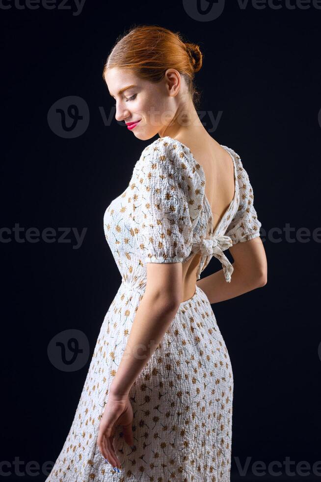 A young redhear girl with clean skin wearing black gloves. Beauty portrait of a woman on a black background in the studio. photo