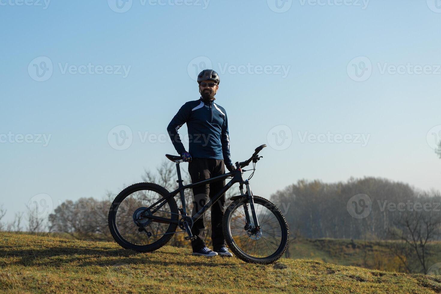 Cyclist in pants and fleece jacket on a modern carbon hardtail bike with an air suspension fork rides off-road. photo