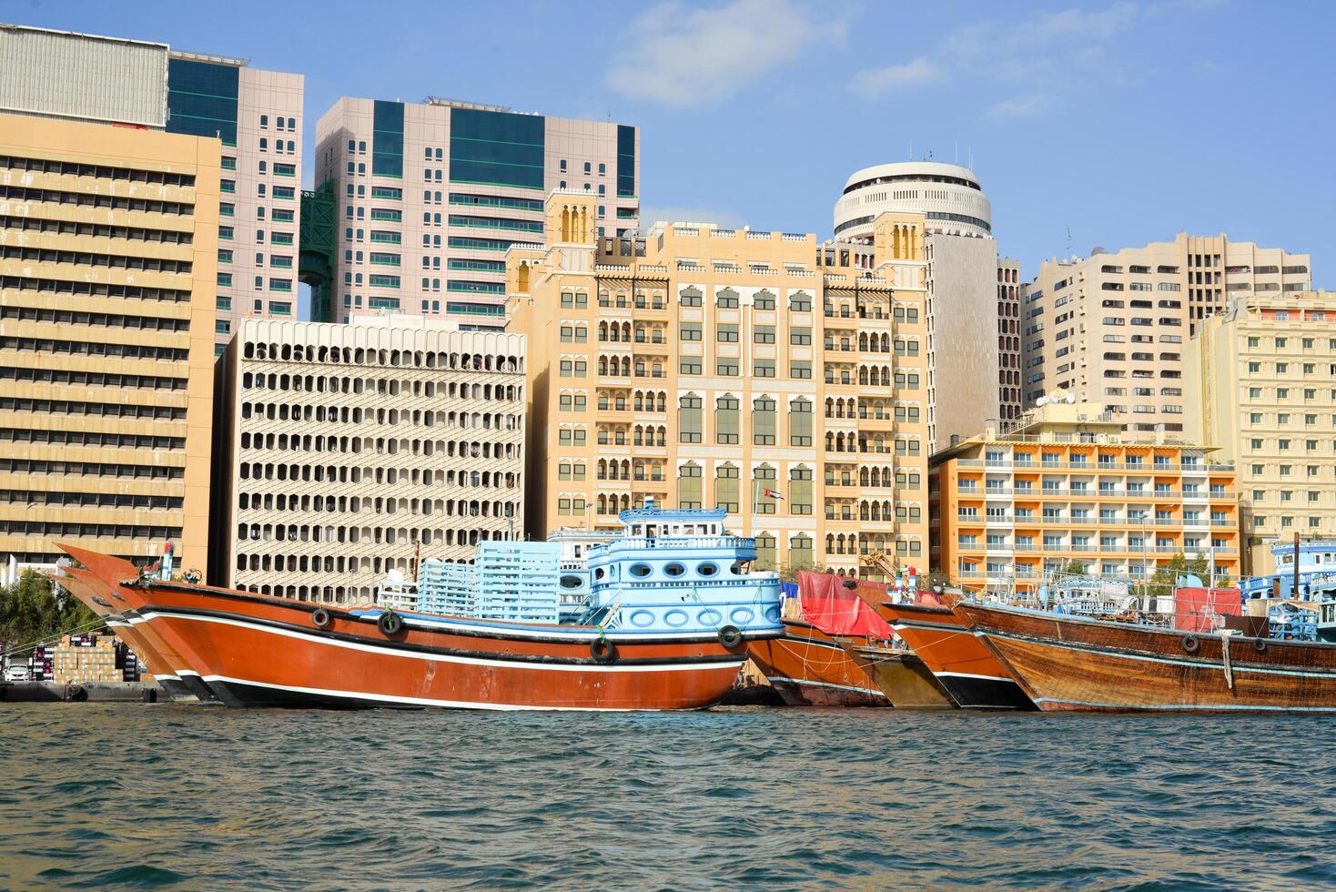 Dubai, United Arab Emirates - February 14, 2023 Traditional wooden tourist boats, abra water taxis and modern sailboats use Dubai Creek in Deira, photo